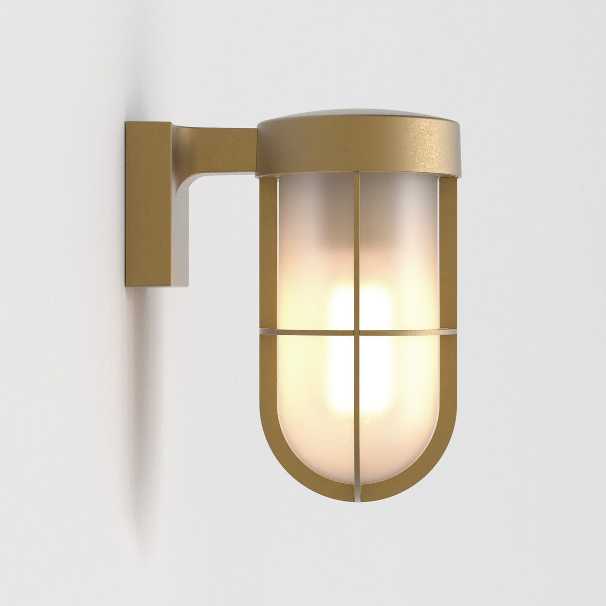 Brass wall light with a frosted glass shade and a protective cage, casting a soft glow
