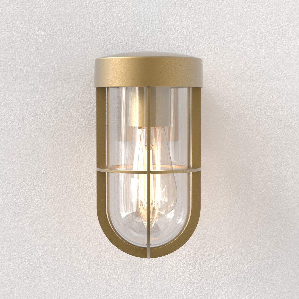 Brass wall light with a clear glass shade and visible filament bulb