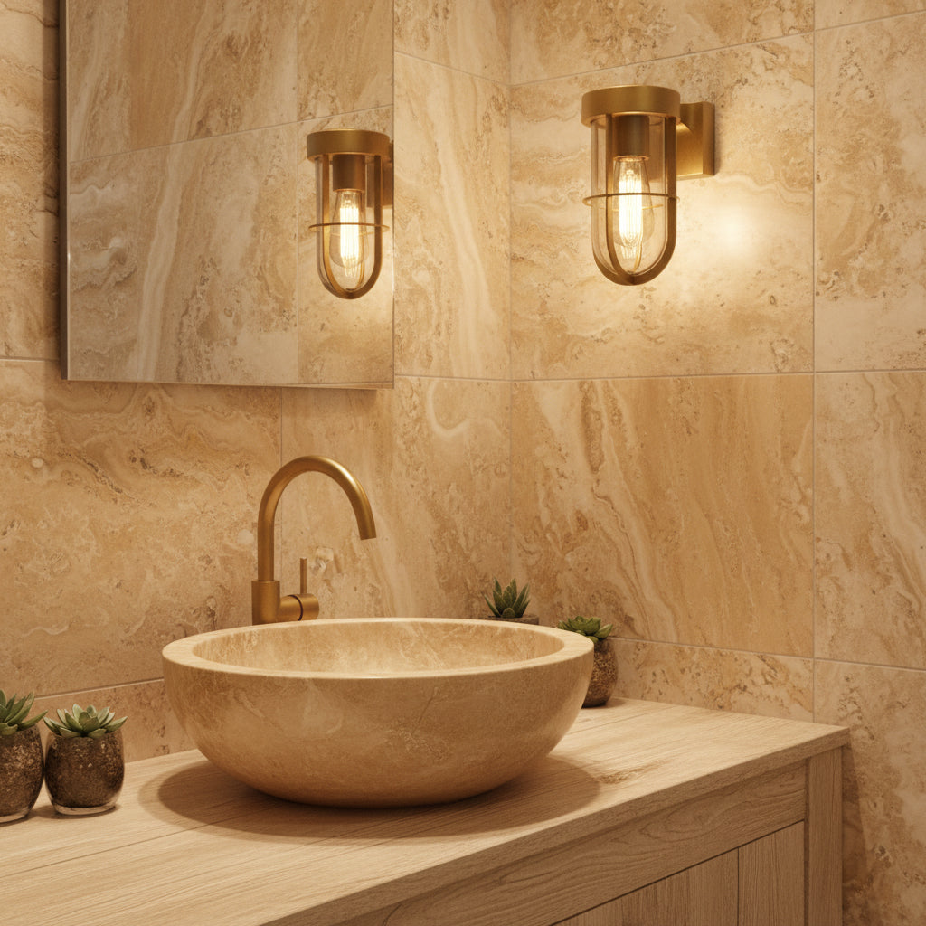 Bathroom vanity with a round stone sink, gold faucet, and two gold wall sconces