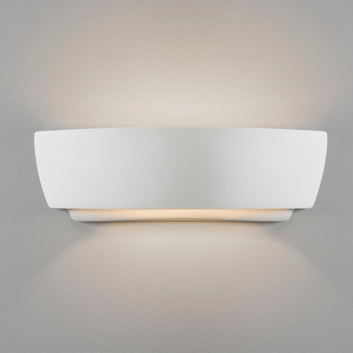 White ceramic wall light with a curved top and bottom, casting light upwards and downwards