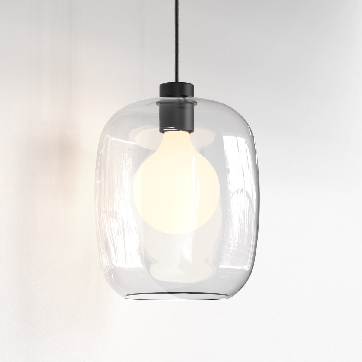 Clear glass pendant light with a black top and a glowing white bulb