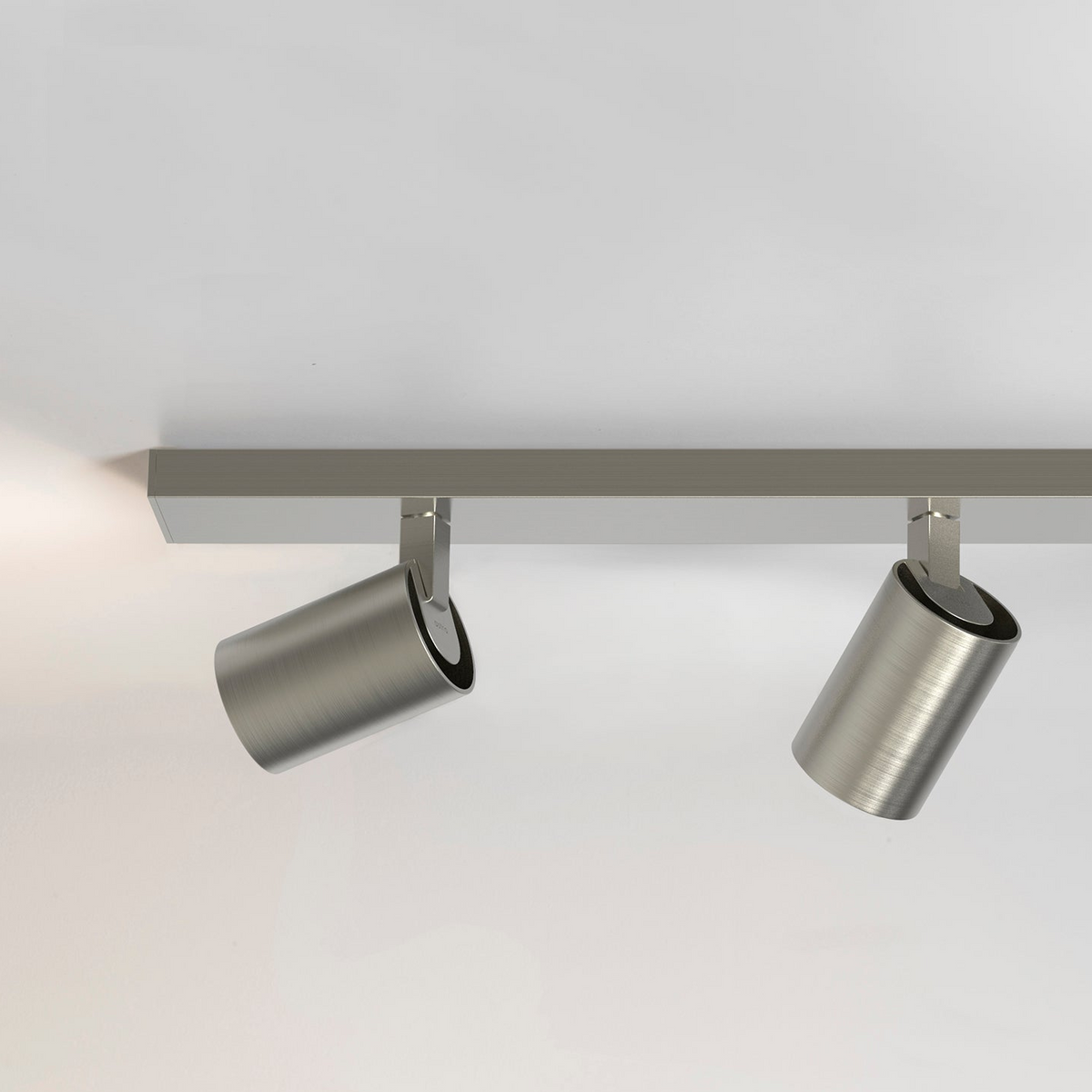 Two brushed metal cylindrical track lights on a silver track against a white ceiling