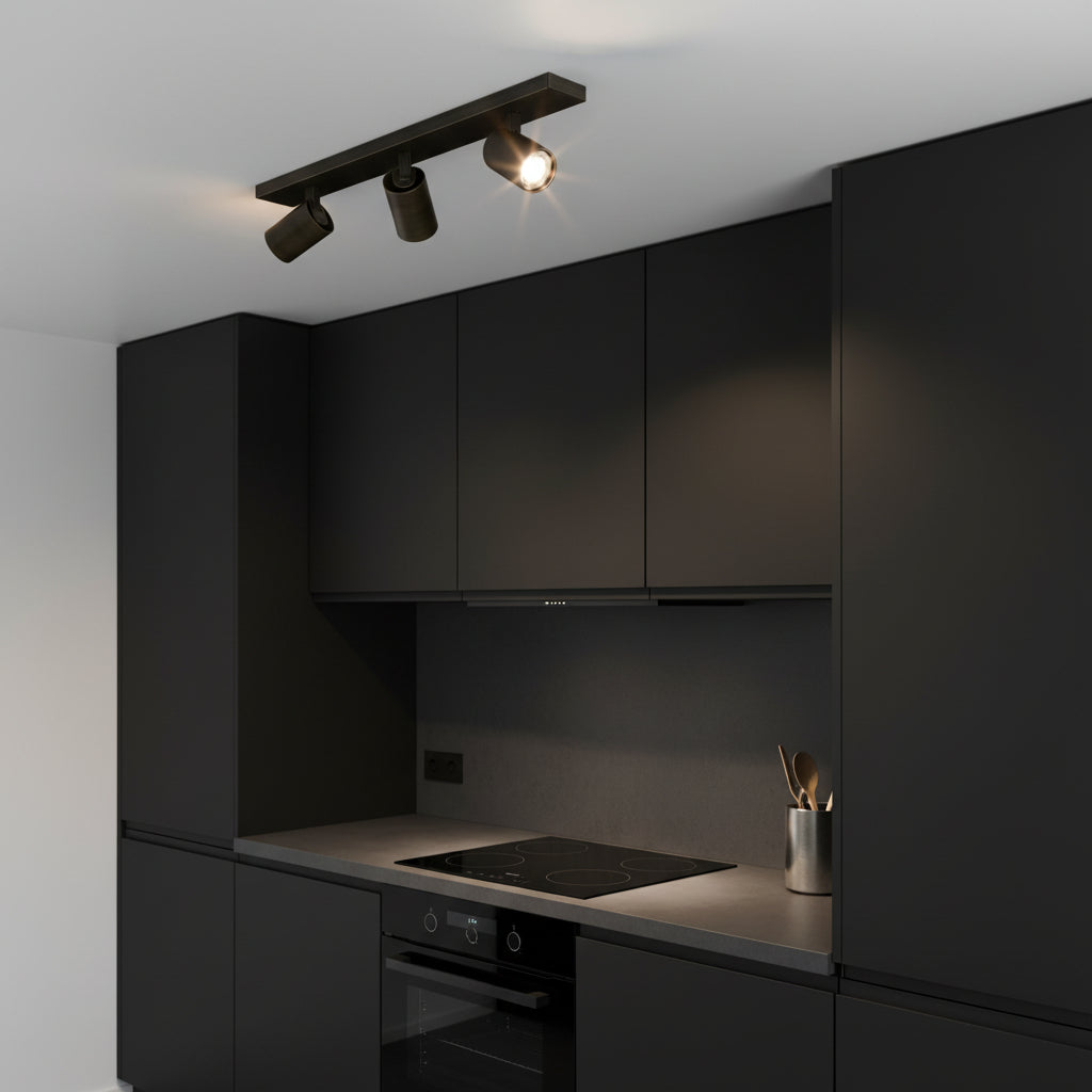 Black track lighting with three spotlights on a white ceiling above a modern black kitchen