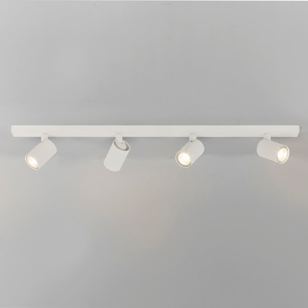 Four white track lights on a white track bar against a light gray background