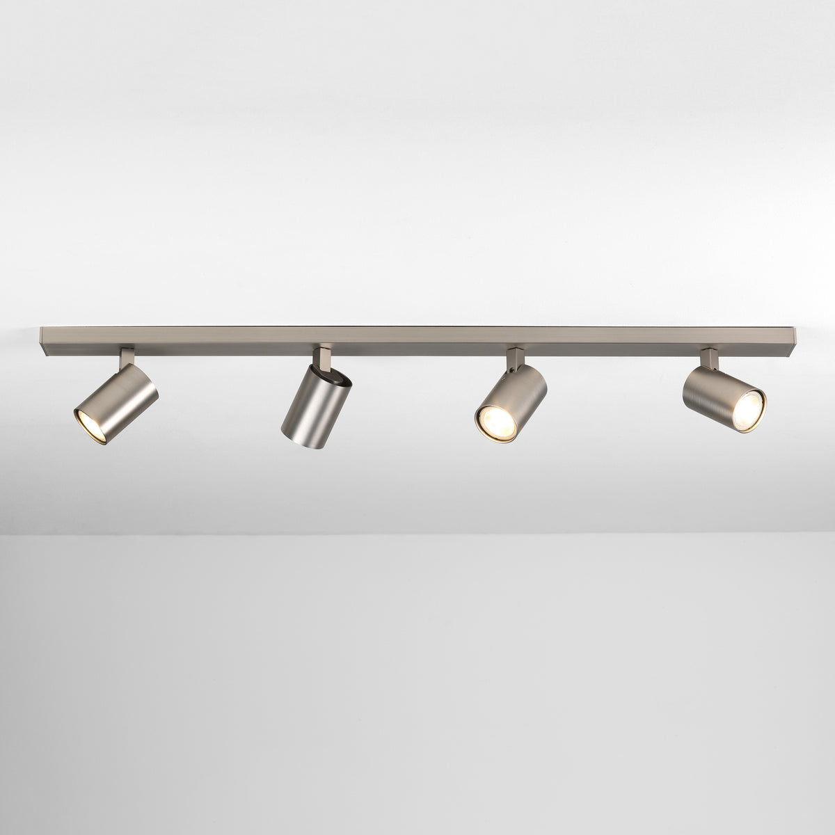 Four brushed metal cylindrical spotlights on a track light fixture