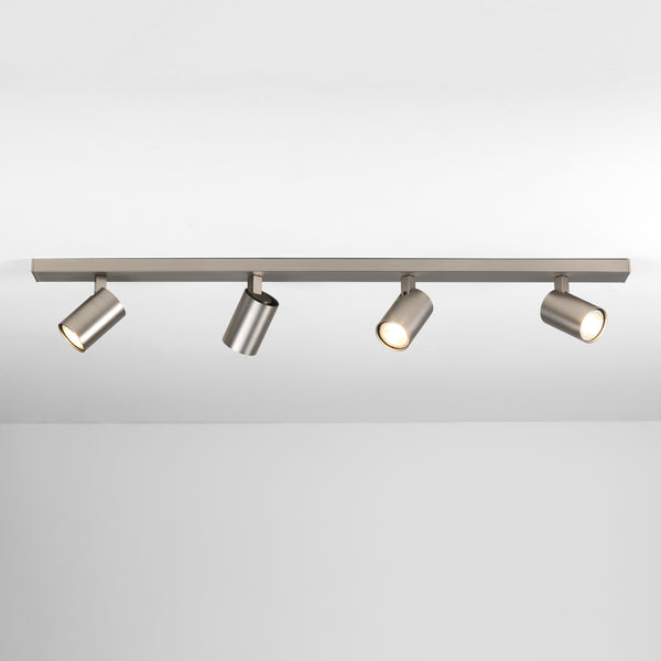 Four brushed metal cylindrical spotlights on a track light fixture