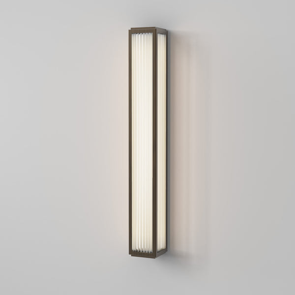 Rectangular wall sconce with a bronze frame and vertical fluted glass panels