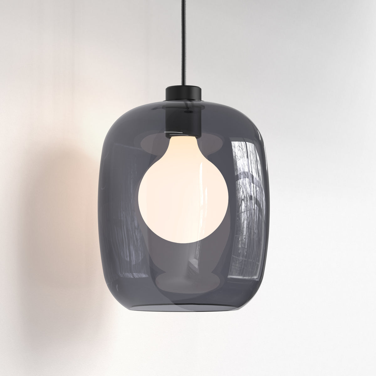 Smoked glass pendant light with a white bulb against a white wall