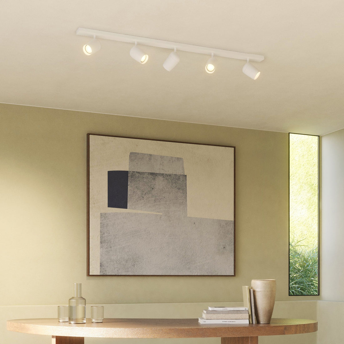 White track lighting with five spotlights on a ceiling above a wooden table with decor