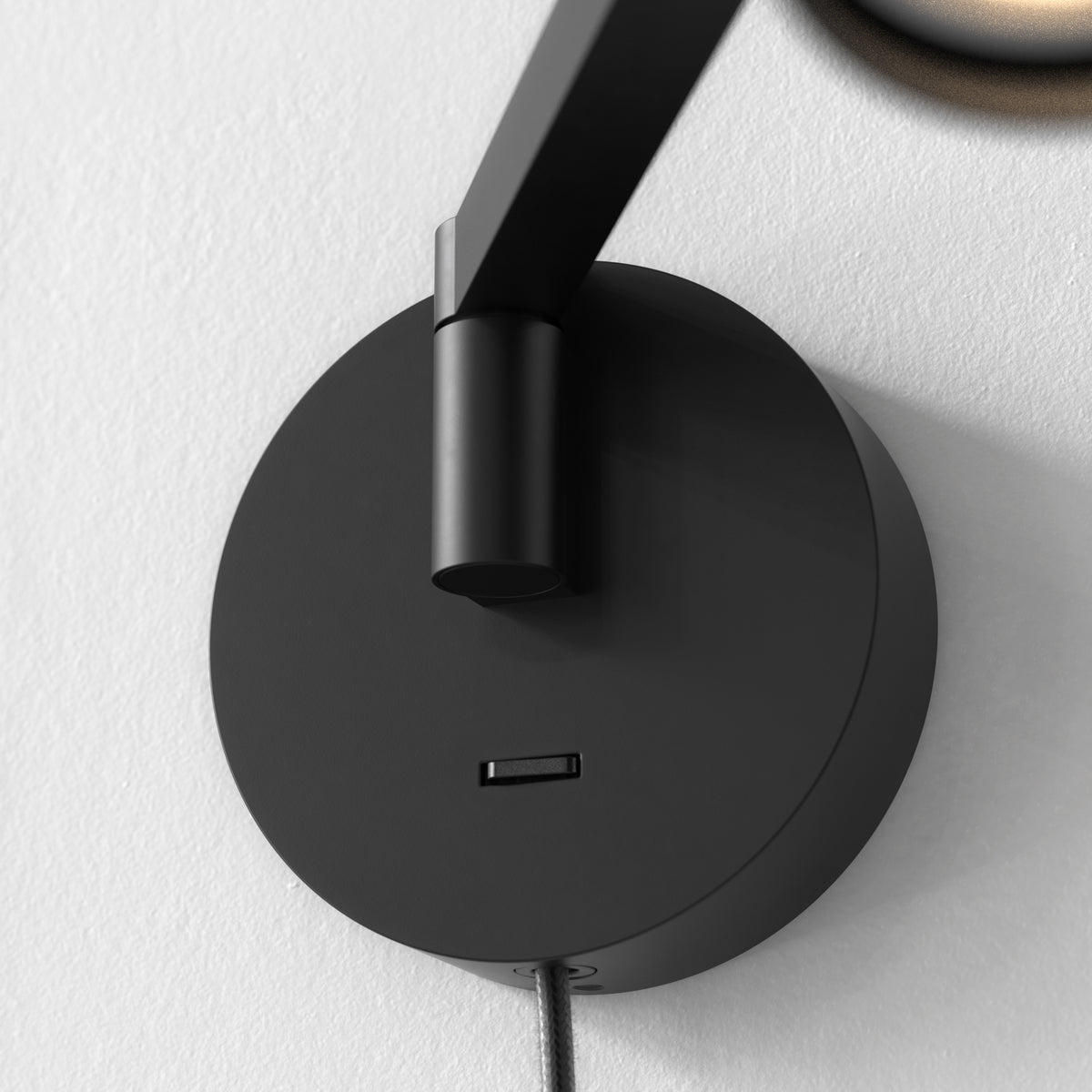 Black circular wall mount with a USB port and a black arm extending upwards