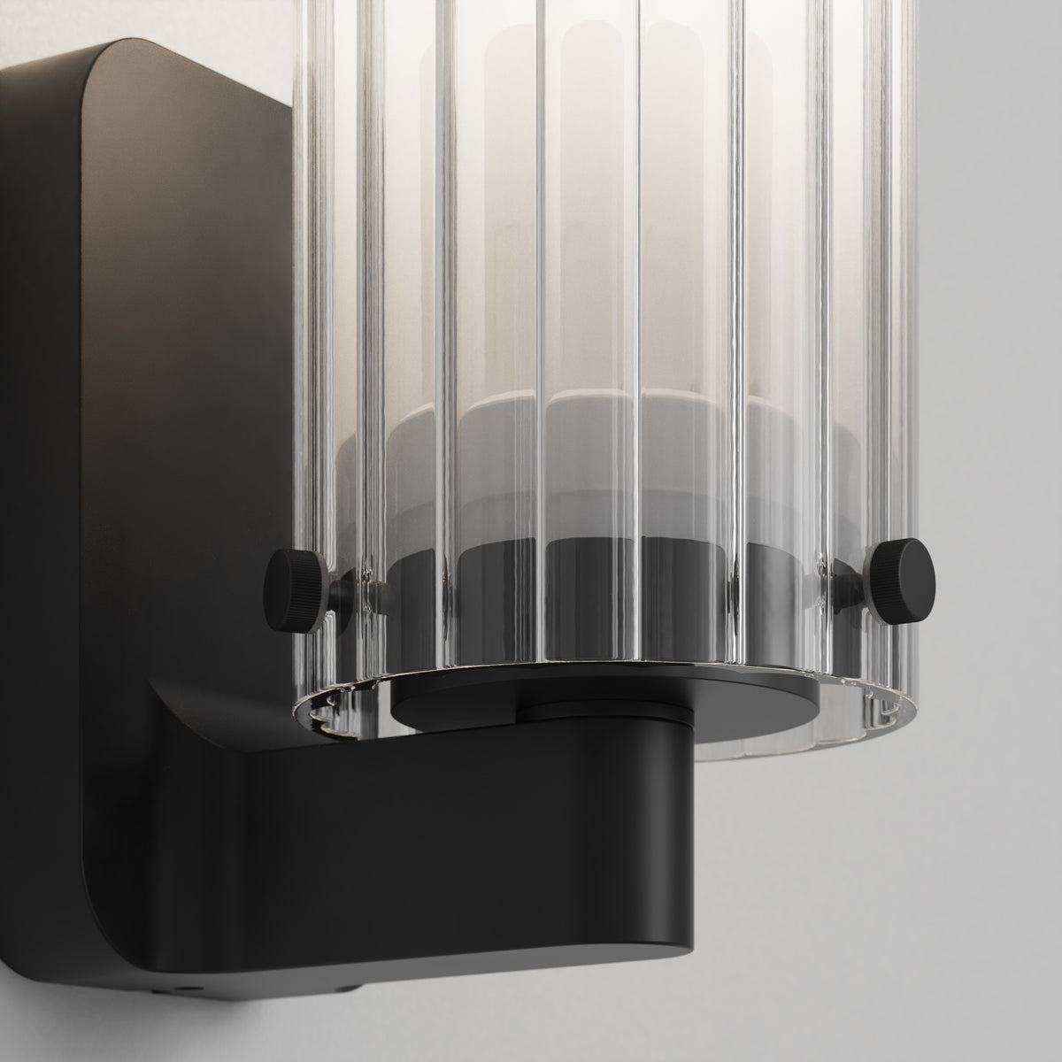 Close up of a black wall sconce with a clear fluted glass shade