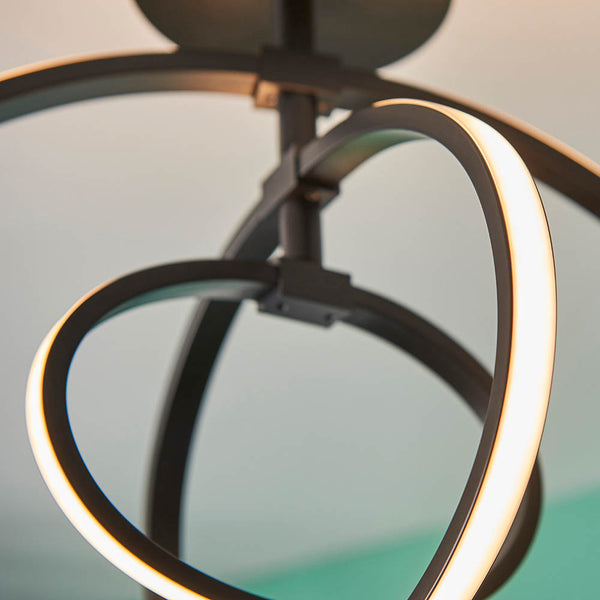 Close-up of a modern black ceiling light with intertwined oval rings, one of which is brightly illuminated.