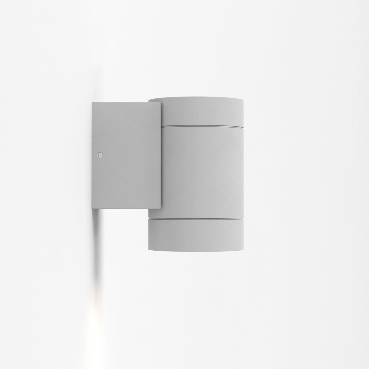 Grey cylindrical outdoor wall light with light shining downwards