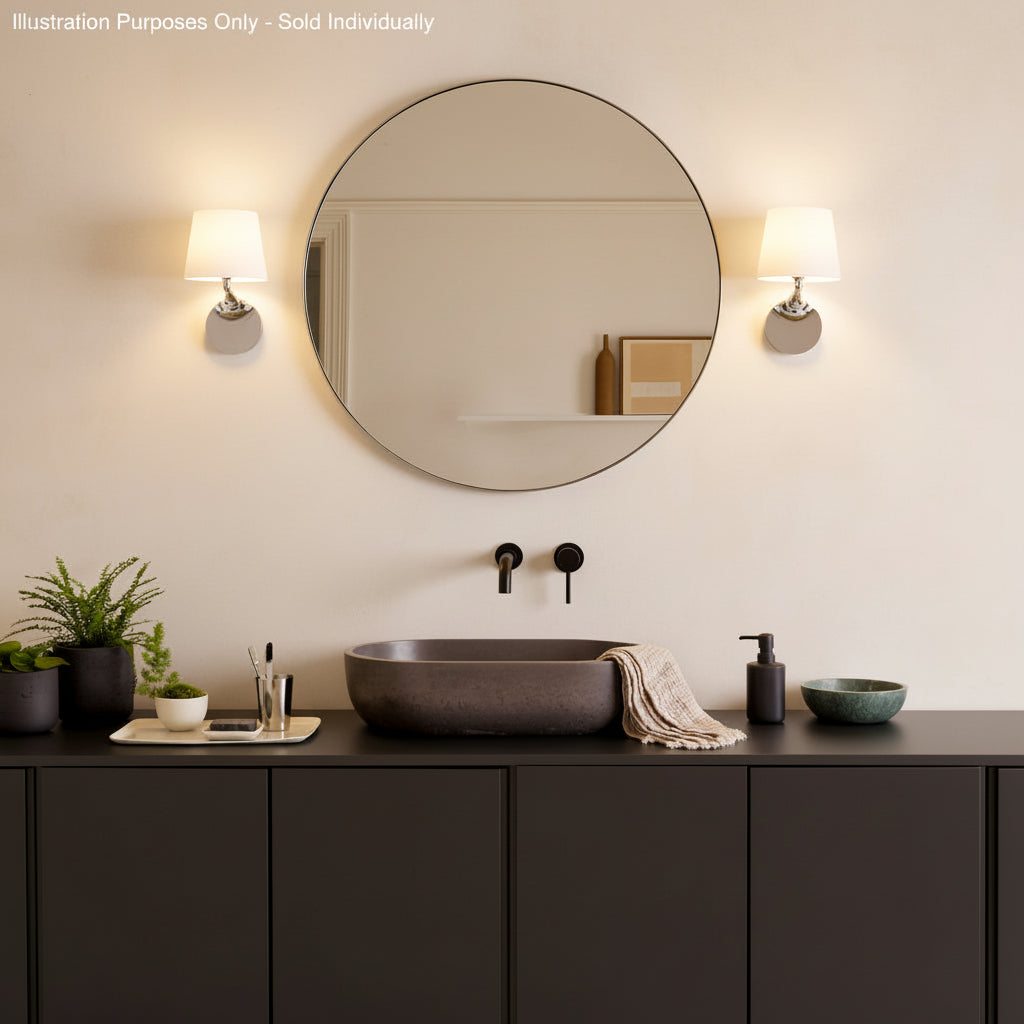Bathroom with a round mirror, two wall sconces, a dark basin, and dark cabinets