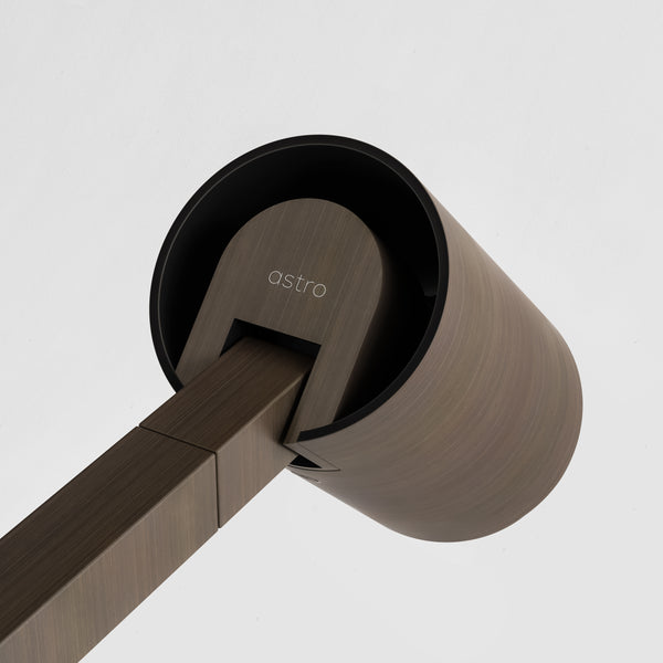 Astro logo on a cylindrical light fixture with a brushed bronze finish