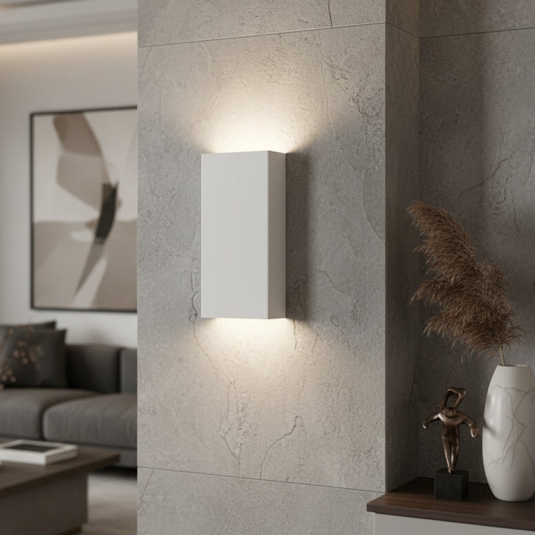 White rectangular wall sconce light fixture mounted on a gray stone wall, illuminating upwards and downwards