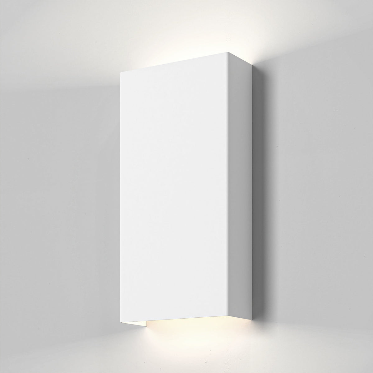 White rectangular wall light fixture casting light upwards and downwards on a light grey wall