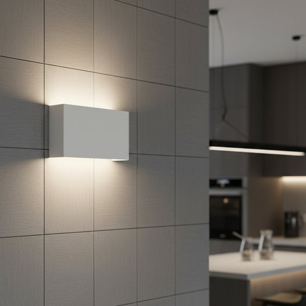 White rectangular wall light on a tiled wall, illuminating the space above and below it