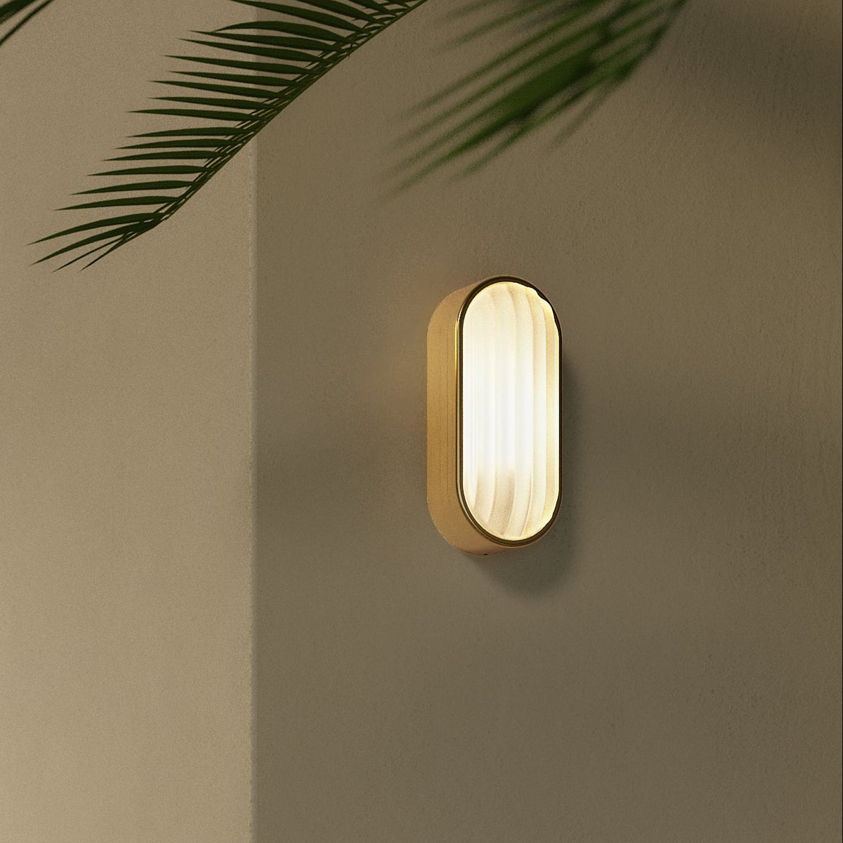 Astro Montreal Oval IP44 Exterior Wall Light in Brushed Brass mounted on a wall with a plant