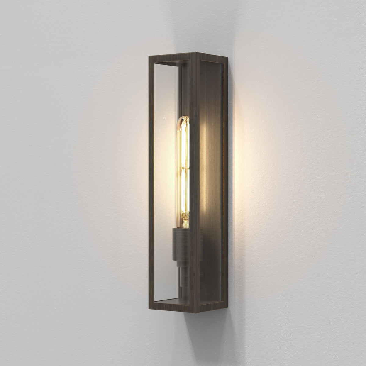 Rectangular wall sconce with a dark bronze finish and a clear glass panel, housing a glowing filament bulb