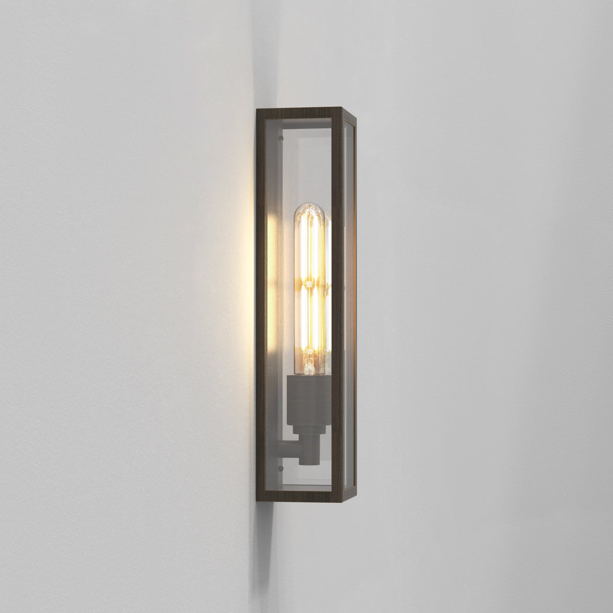 Rectangular wall sconce with a dark bronze frame and clear glass panels, housing an exposed filament bulb