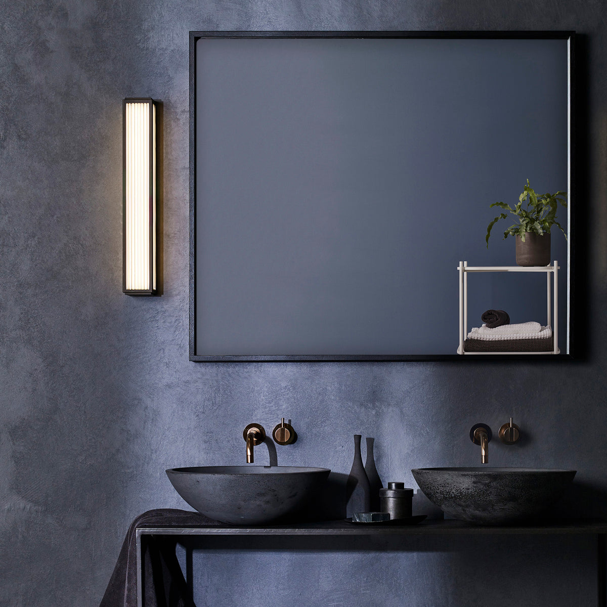 Bathroom with dark grey textured walls, two black stone sinks, and a large mirror