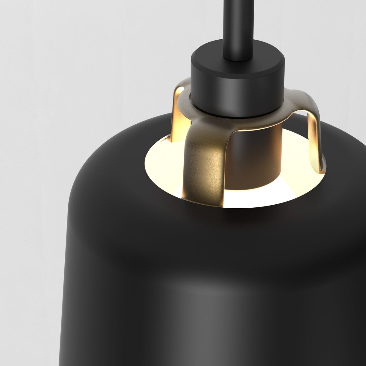 Close up of a black pendant light with a brass accent and a glowing bulb