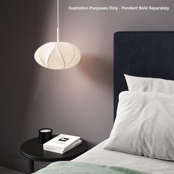 White pendant light above a black bedside table with books and a candle next to a bed with white pillows