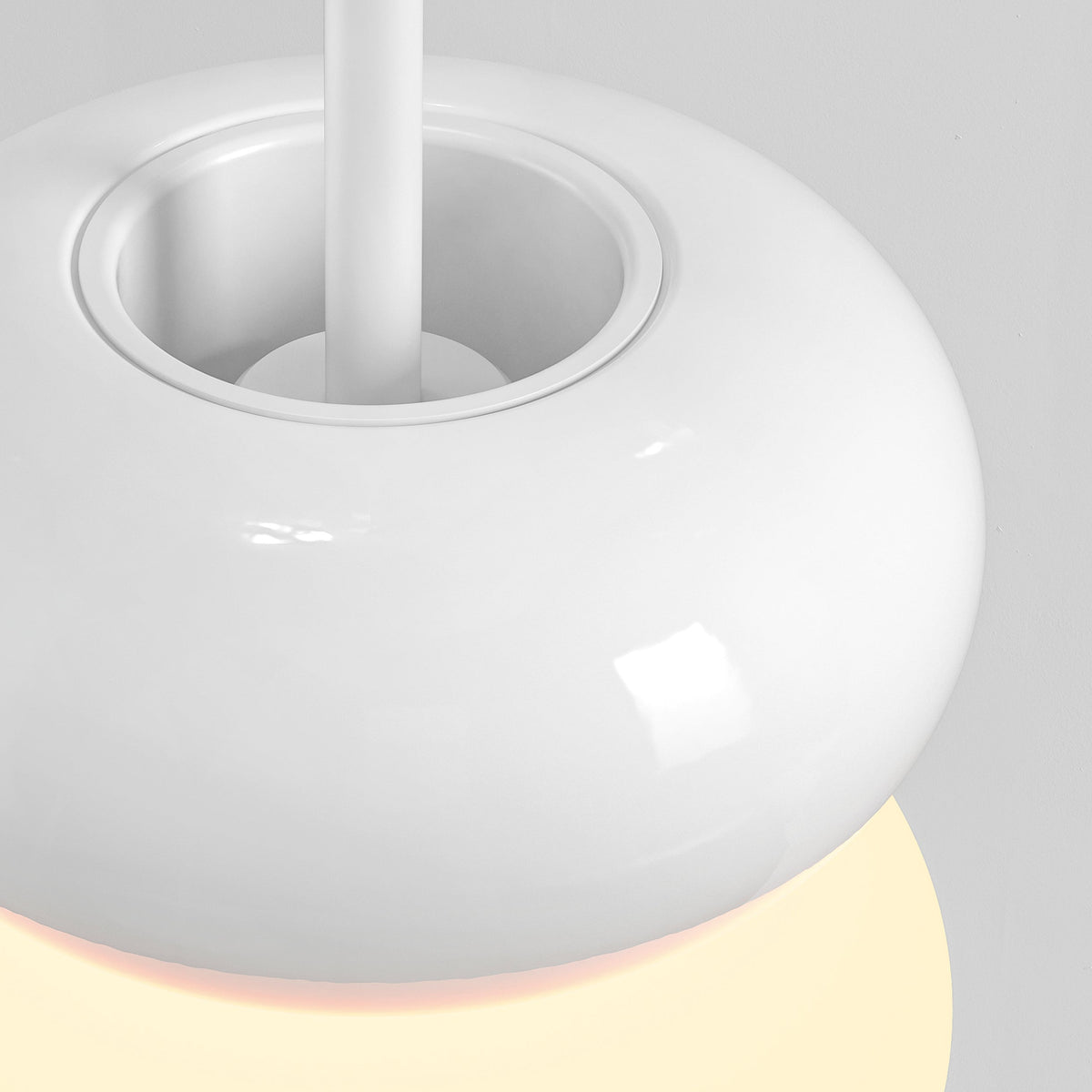 White pendant light with a circular base and a glowing yellow light underneath