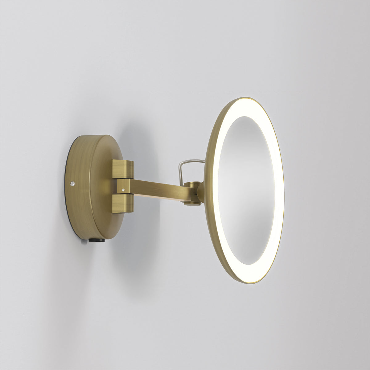 Round illuminated magnifying mirror with an antique brass finish, mounted on a wall with an extendable arm