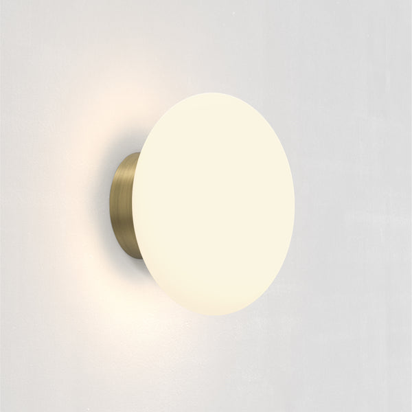 Round wall light with a brass base and a white spherical shade