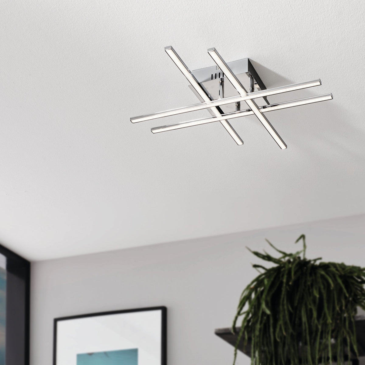Chrome ceiling light with four intersecting bars, each containing an LED strip, mounted on a white ceiling