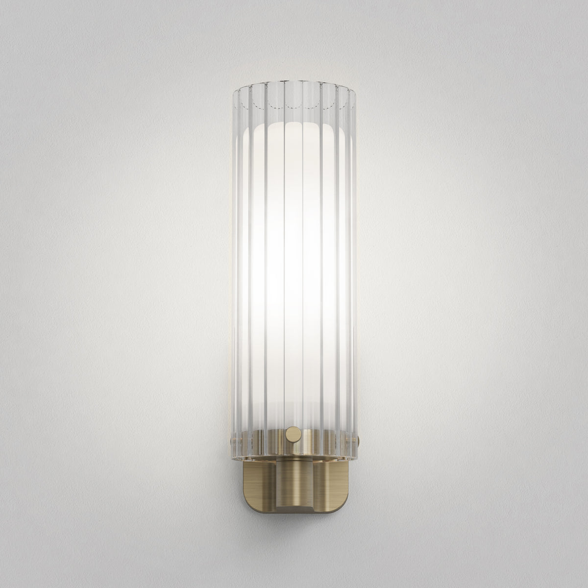 Fluted glass wall sconce with a brass base and a white light