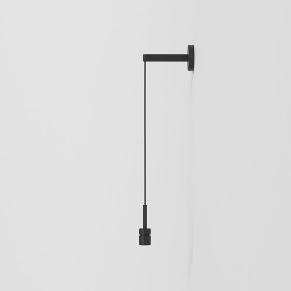 Black wall light with a square base and a long cord ending in a cylindrical bulb holder