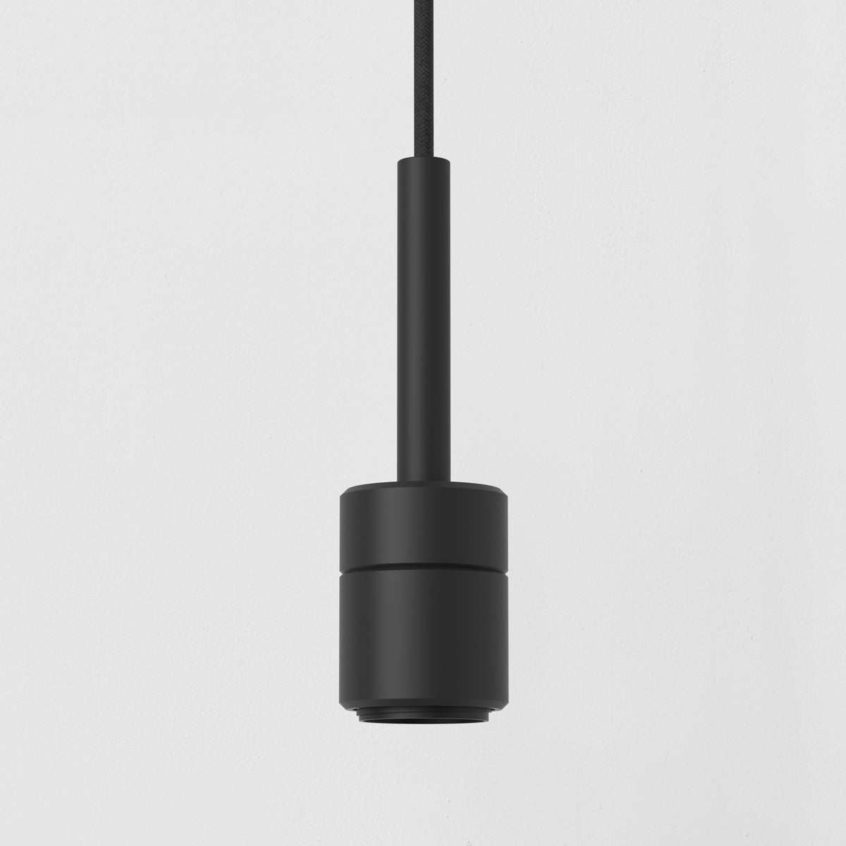 Black cylindrical pendant light with a braided cord against a white wall