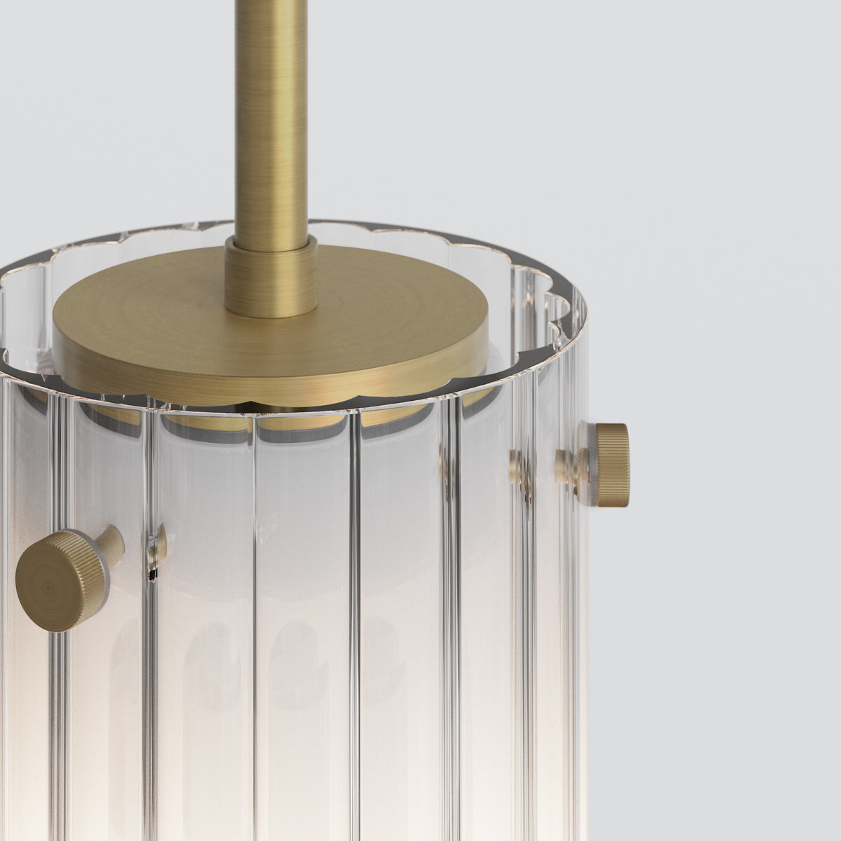 Close up of a clear glass pendant light with vertical fluting and brass accents