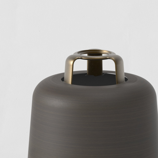 Close up of a dark bronze lamp base with a brass-colored finial