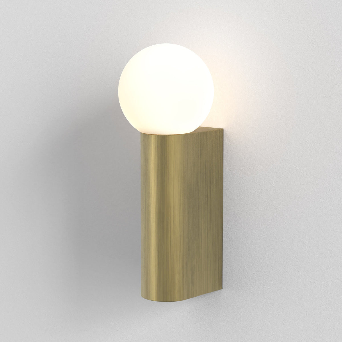 Brushed brass wall light with a glowing spherical white glass shade