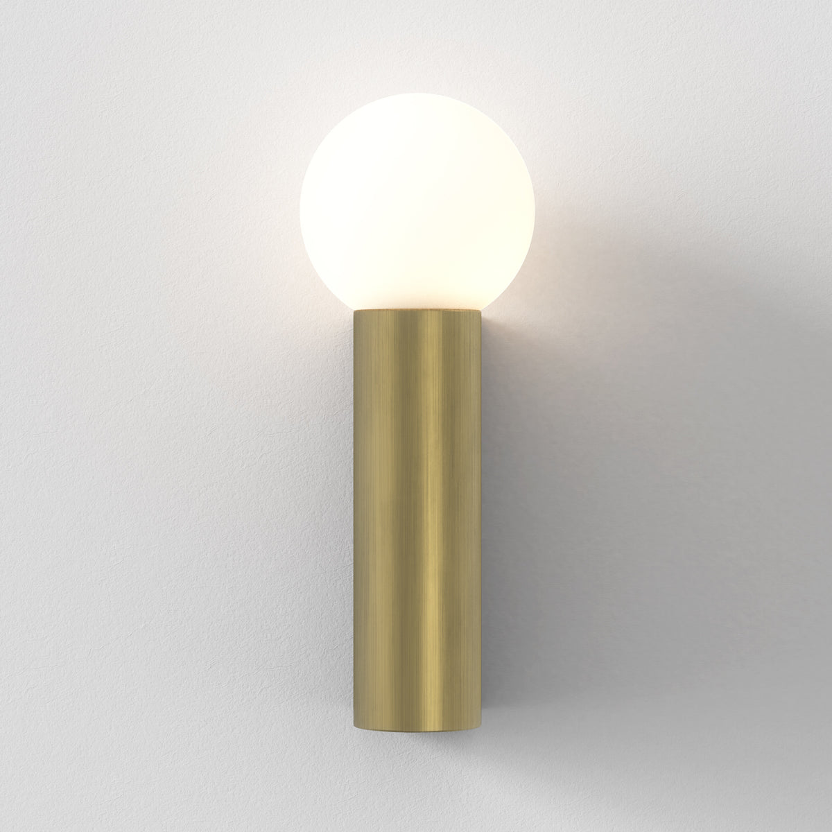 Brass wall sconce with a spherical white light on a white wall