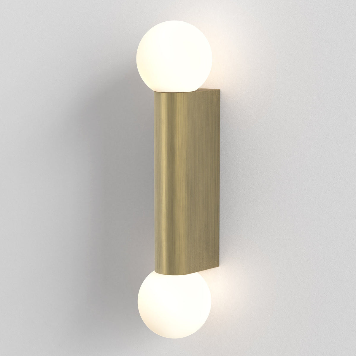 Brass wall light with two spherical white glass shades, one at the top and one at the bottom