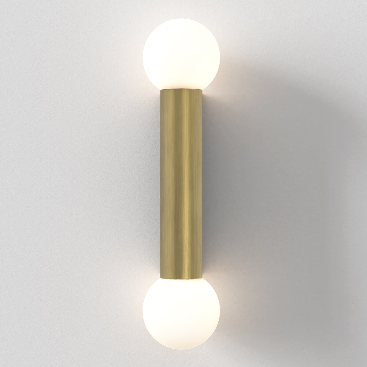 Brass wall sconce with two spherical white glass shades, one at each end of the brass cylinder
