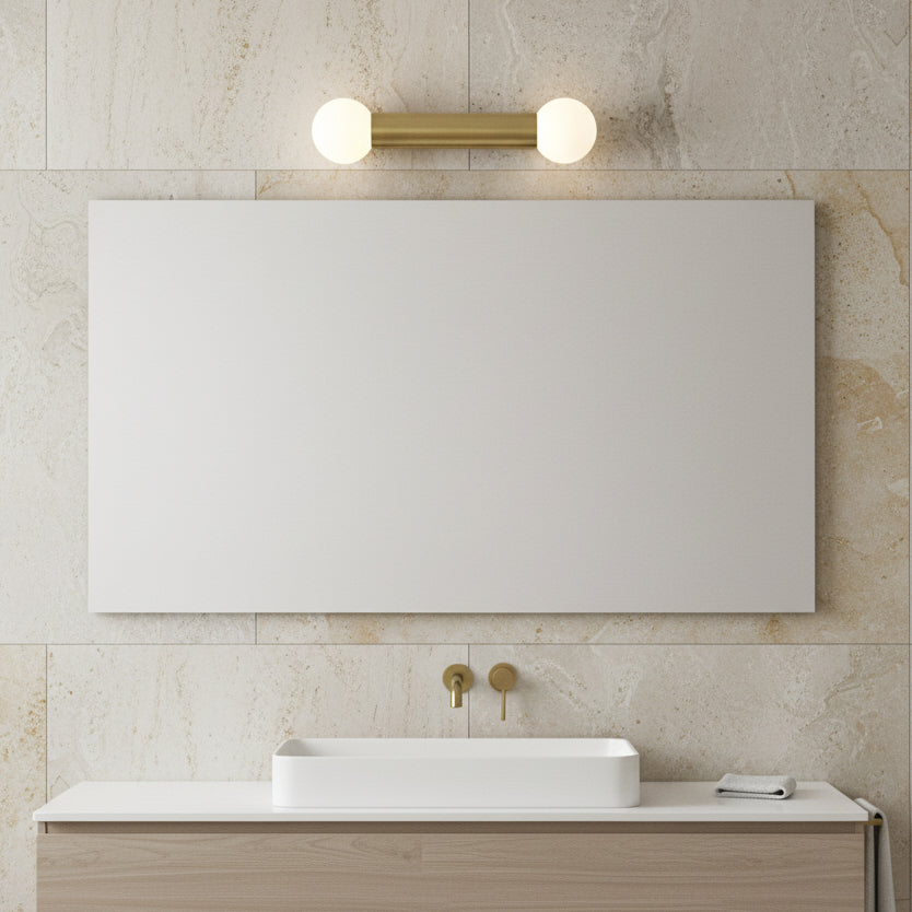 Bathroom with rectangular mirror, brass light fixture, white rectangular sink, and brass wall-mounted taps