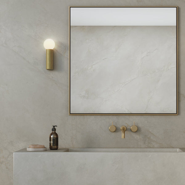 Bathroom vanity with a light grey marble countertop and wall. Gold fixtures and a rectangular mirror