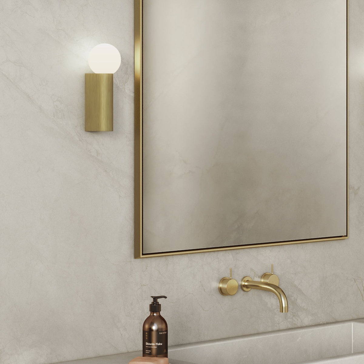 Bathroom vanity with a gold framed mirror, gold wall-mounted faucet, and a gold wall sconce