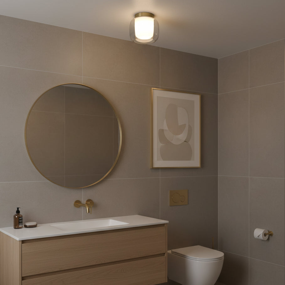 Bathroom with a round mirror, wooden vanity, white toilet, and a ceiling light