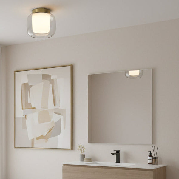 A ceiling light with a brass base and a clear glass shade over a white diffuser