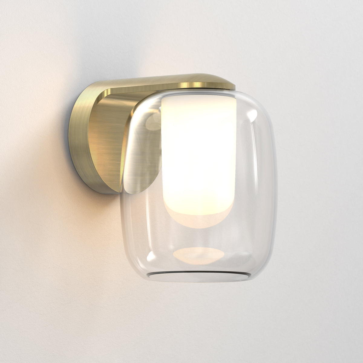 Brass wall light with a clear glass shade and an illuminated white inner diffuser