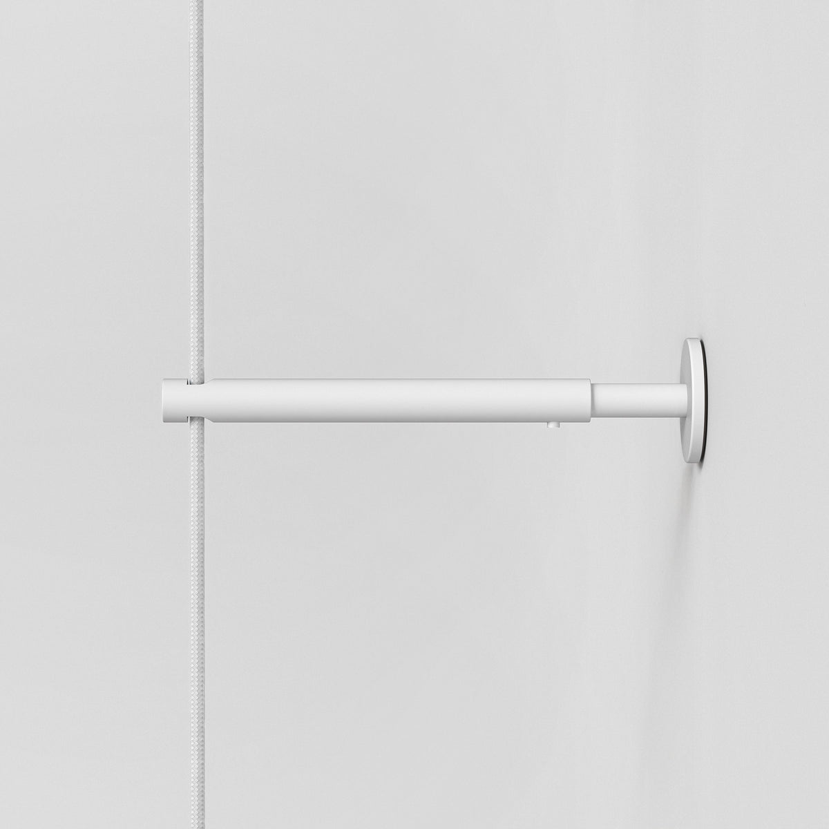 White curtain rod with a white braided cord on a white wall