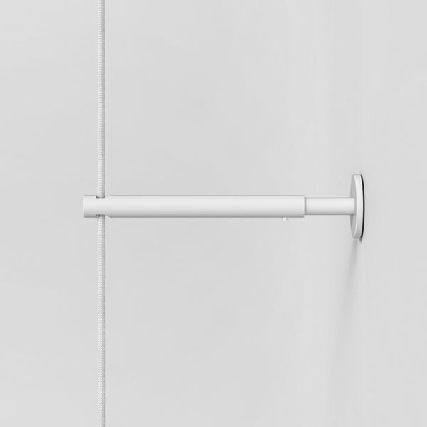 White curtain rod with a white braided cord on a white wall
