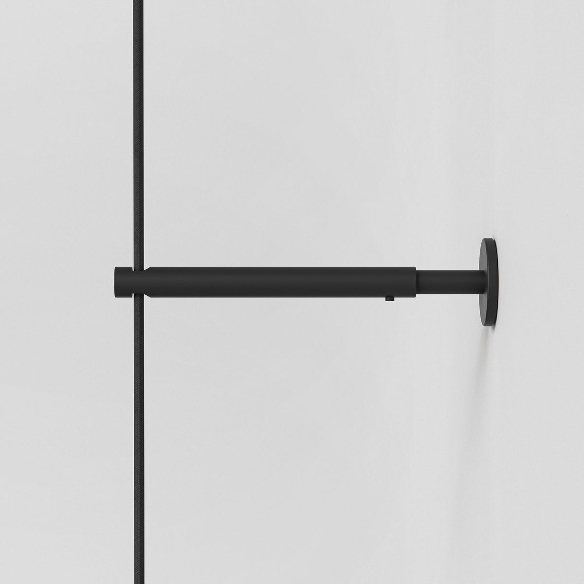 Black metal shower arm with a black braided hose attached to a white wall